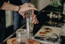 Najlepsze przepisy na proste drinki w domu: jak zacząć domowy bar krok po kroku Barman w kuchni potrząsa shakerem, przygotowując prosty domowy drink