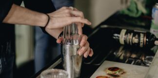 Barman w kuchni potrząsa shakerem, przygotowując prosty domowy drink