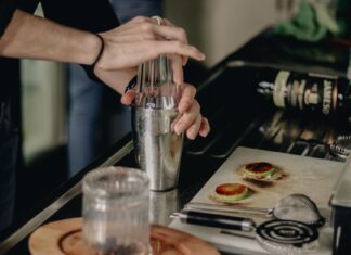 Najlepsze przepisy na proste drinki w domu: jak zacząć domowy bar krok po kroku Barman w kuchni potrząsa shakerem, przygotowując prosty domowy drink