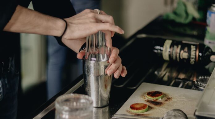 Barman w kuchni potrząsa shakerem, przygotowując prosty domowy drink