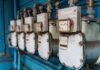 AI w energetyce przemysłowej: redukcja zużycia mediów i śladu węglowego Inteligentne liczniki mediów na niebieskiej ścianie w zakładzie przemysłowym