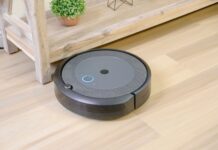 Ranking robotów sprzątających 2024 – które modele naprawdę warto kupić Robot sprzątający na drewnianej podłodze obok doniczkowej rośliny