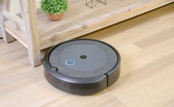 Robot sprzątający na drewnianej podłodze obok doniczkowej rośliny