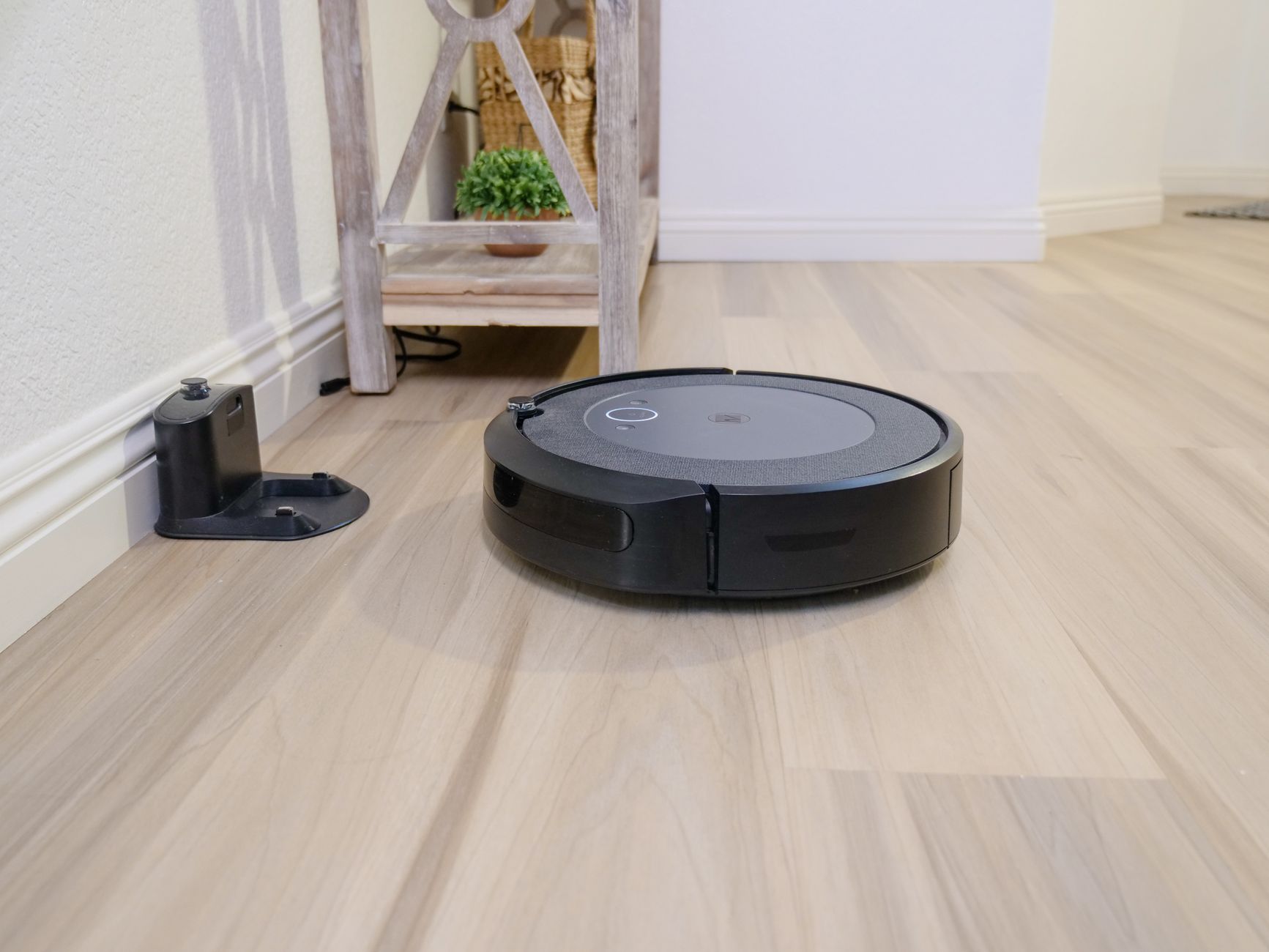 Robot sprzątający na drewnianej podłodze obok stacji dokującej