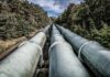Jak poukładać pipeline CI/CD dla monolitu, a jak dla architektury mikroserwisowej Duże rury przemysłowe biegnące przez zielony las