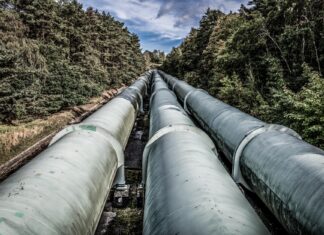 Jak poukładać pipeline CI/CD dla monolitu, a jak dla architektury mikroserwisowej Duże rury przemysłowe biegnące przez zielony las