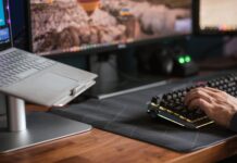 Mężczyzna piszący na podświetlanej klawiaturze obok laptopa