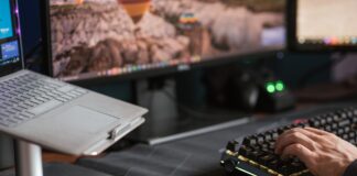 Mężczyzna piszący na podświetlanej klawiaturze obok laptopa