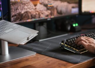 Klawiatury mechaniczne dla programistów: test przełączników i ergonomii Mężczyzna piszący na podświetlanej klawiaturze obok laptopa