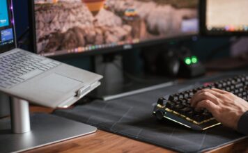 Mężczyzna piszący na podświetlanej klawiaturze obok laptopa