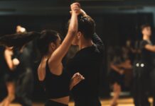 Podstawy techniki tańca latino dla początkujących: kluczowe zasady pracy ciała, rytmu i prowadzenia Para tańczy tango latino w studiu przed obserwującymi kursantami
