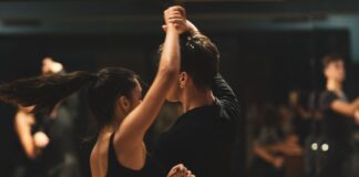 Para tańczy tango latino w studiu przed obserwującymi kursantami