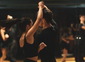 Podstawy techniki tańca latino dla początkujących: kluczowe zasady pracy ciała, rytmu i prowadzenia Para tańczy tango latino w studiu przed obserwującymi kursantami
