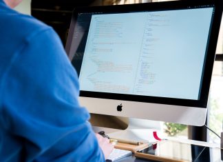 NestJS w praktyce: modularny framework Node.js dla dużych projektów backendowych Programista w niebieskiej koszuli koduje na iMacu nad backendem Node.js