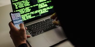 AI w rękach cyberprzestępców: automatyzacja phishingu, kampanii spamowych i skanowania luk Haker w czarnej bluzie korzysta z netbooka i telefonu w biurze