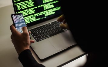 AI w rękach cyberprzestępców: automatyzacja phishingu, kampanii spamowych i skanowania luk Haker w czarnej bluzie korzysta z netbooka i telefonu w biurze