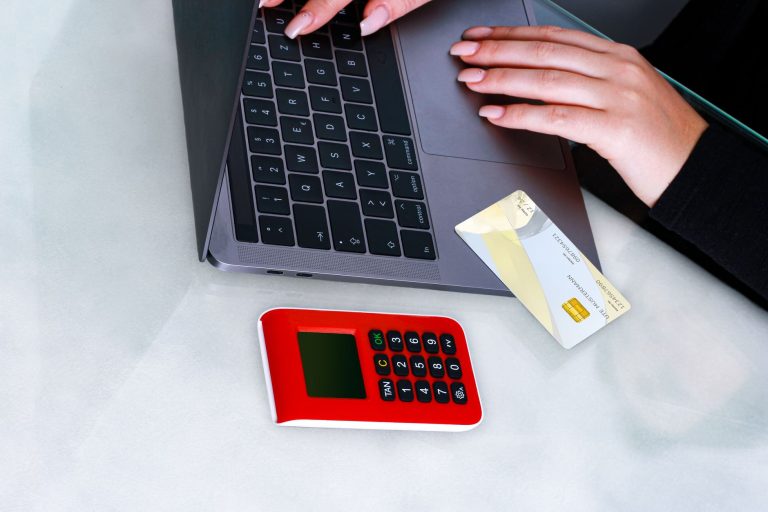 Dłonie przy laptopie z kartą i urządzeniem zabezpieczającym płatność online